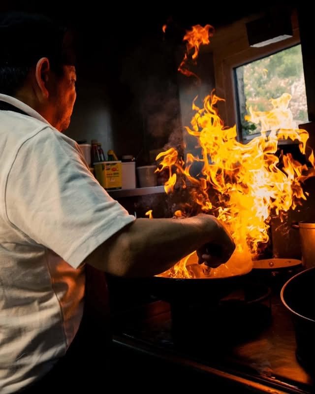 A chef cooking over flames in the restaurant kitchen