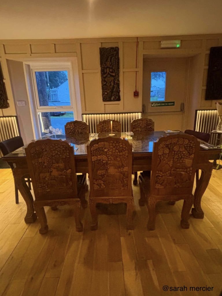 The dining room, with carved hardwood chairs and a long table under warm lighting