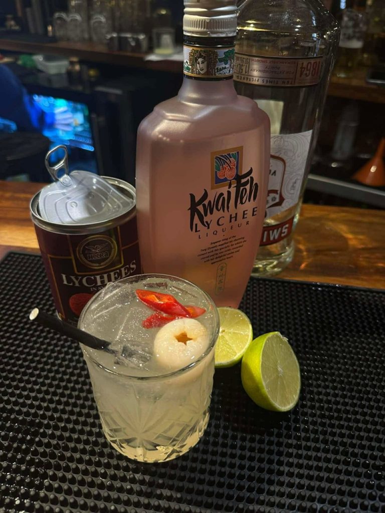 A lychee cocktail on the bar, garnished with lychee and sliced chilli