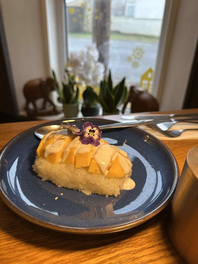 Mango sticky rice with coconut sauce and an edible flower