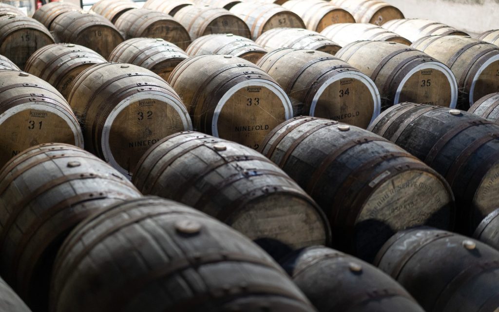 Rows of numbered oak casks maturing rum, several branded Ninefold