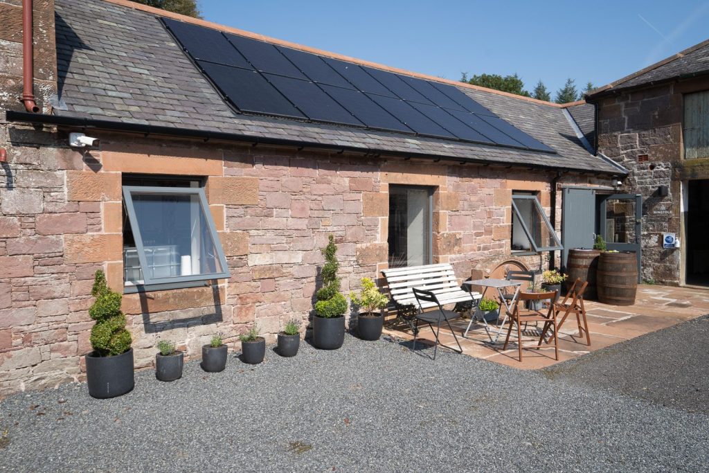 The distillery courtyard, a converted cattle byre of red sandstone with solar panels on the slate roof