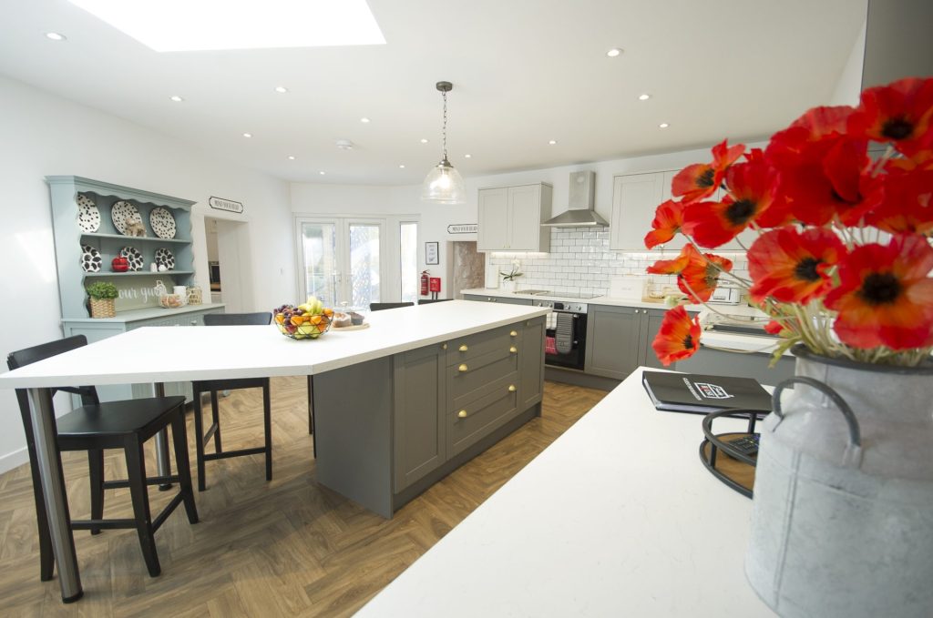 The kitchen and dining room, with a painted dresser, a long island and a run of grey units